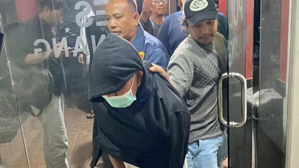 Tersangka mutilasi Nasrun di Tanjungpinang dikawal ketat polisi saat keluar dari gedung Mapolresta dengan wajah tertutup kupluk dan masker.