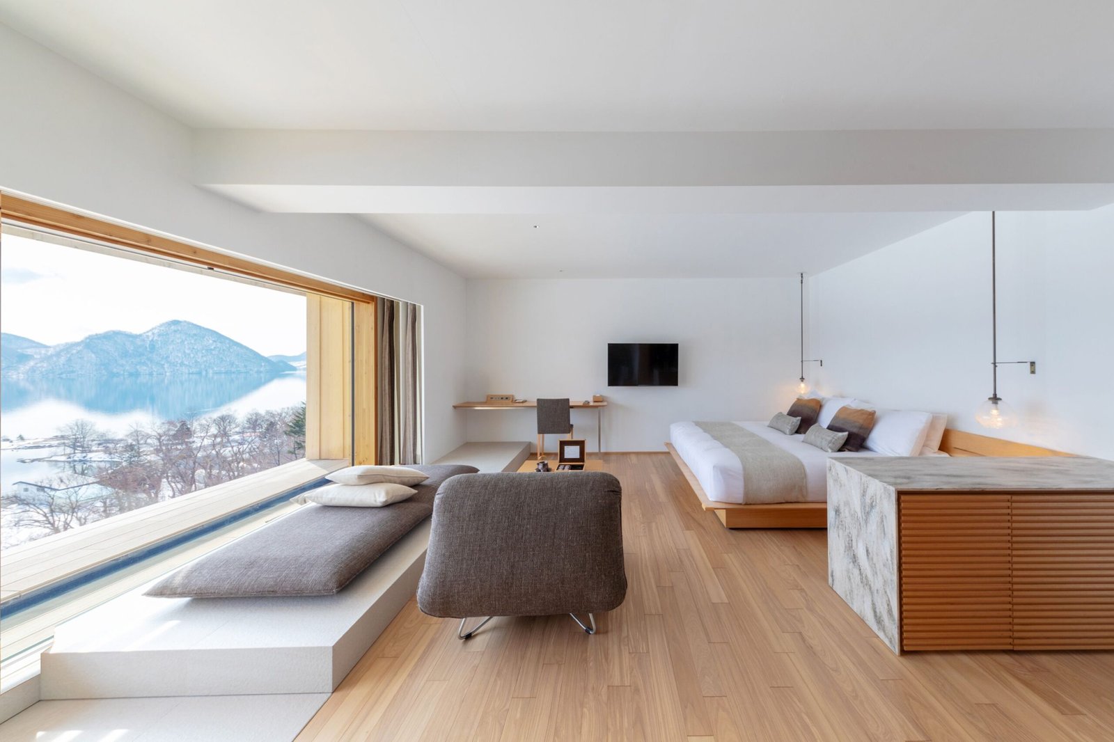Desain arsitektur bagian dalam kamar mewah WE Hotel Toya Dusit Collection di Hokkaido dengan pemandangan langsung ke Danau Toya.
