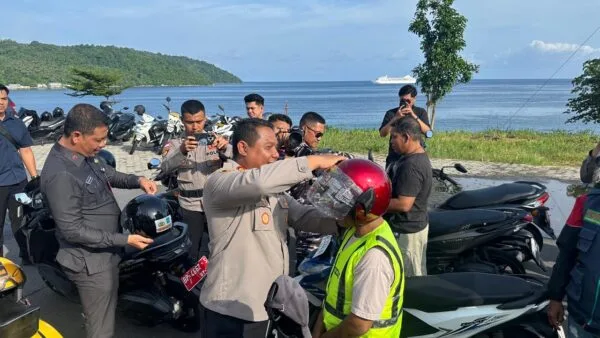 Bupati Aneng bersama Kapolres Anambas AKBP I Gusti Ngurah Agung Budianaloka saat memasangkan helm gratis kepada perwakilan warga di Tarempa (Dok. Istimewa).