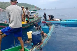 Tim penyelam gabungan dibantu warga nelayan berupaya mengevakuasi pompong yang tenggelam di perairan Pelabuhan Tarempa menggunakan drum plastik pelampung